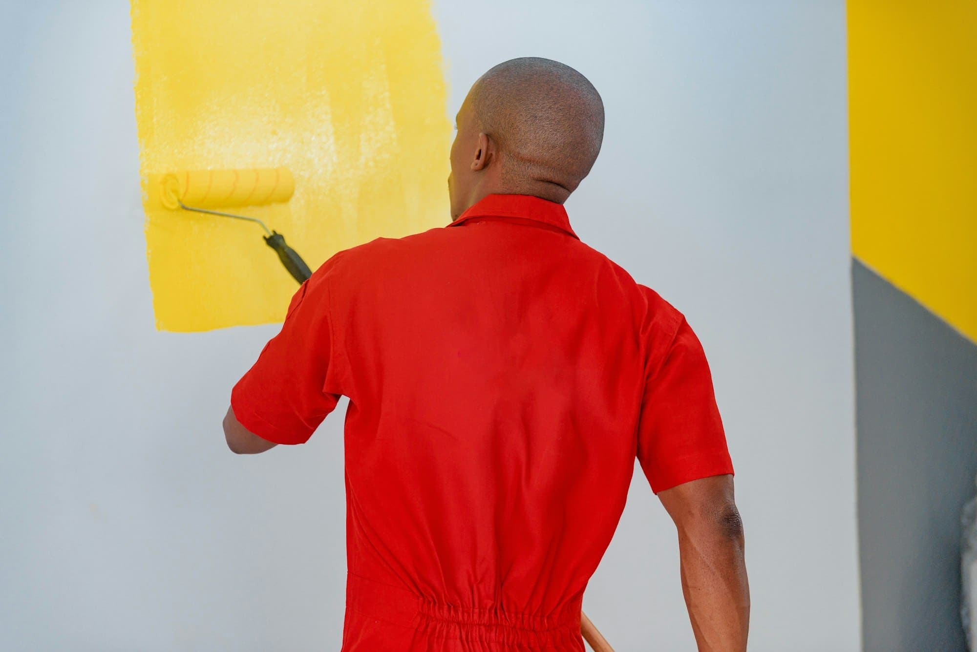 Maler streicht eine Wand mit der Rolle in kräftiger Farbe